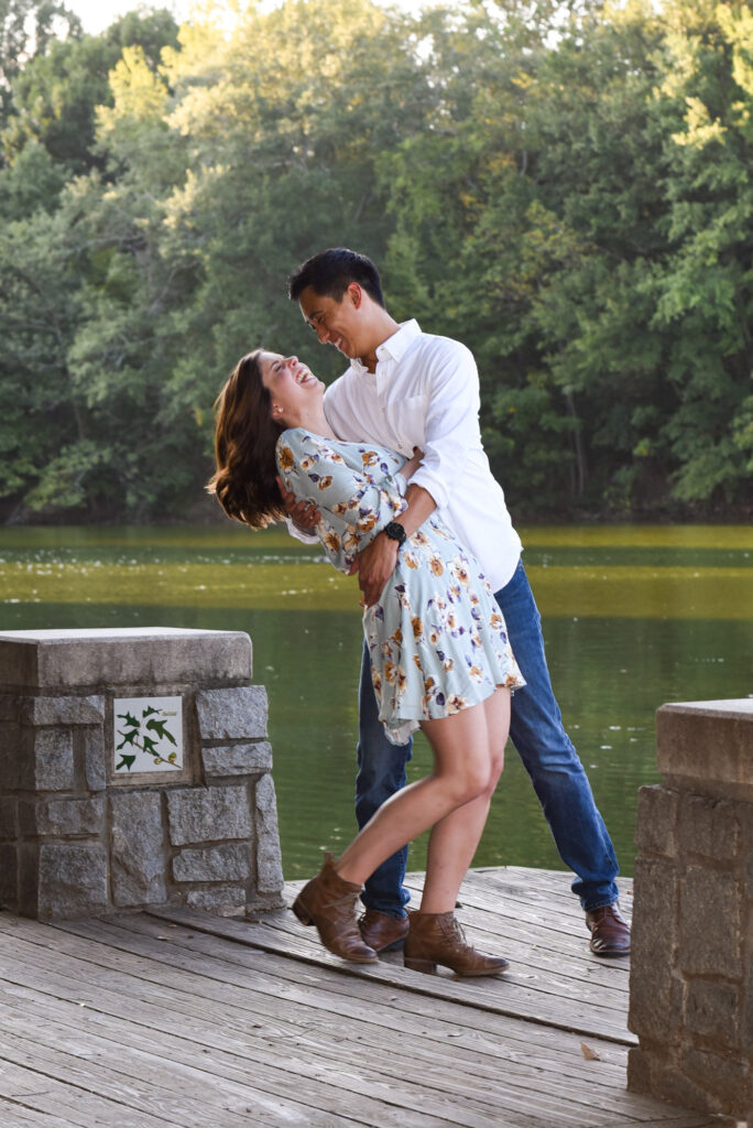 Groom dips his laughing bride near a lake at Piedmont Park in Atlanta, GA