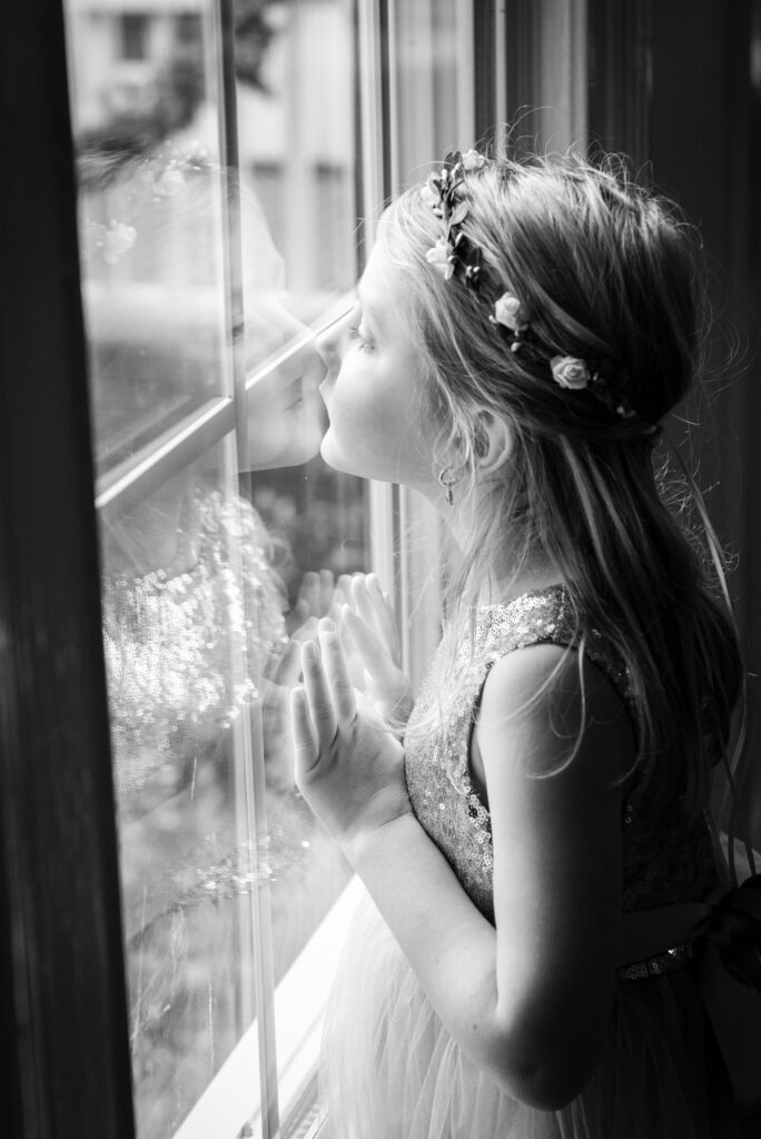 Flower girl pushes her face against the window looking out
