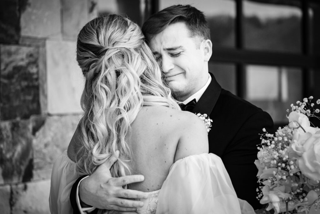 Groom cries as he hugs his bride during the first look