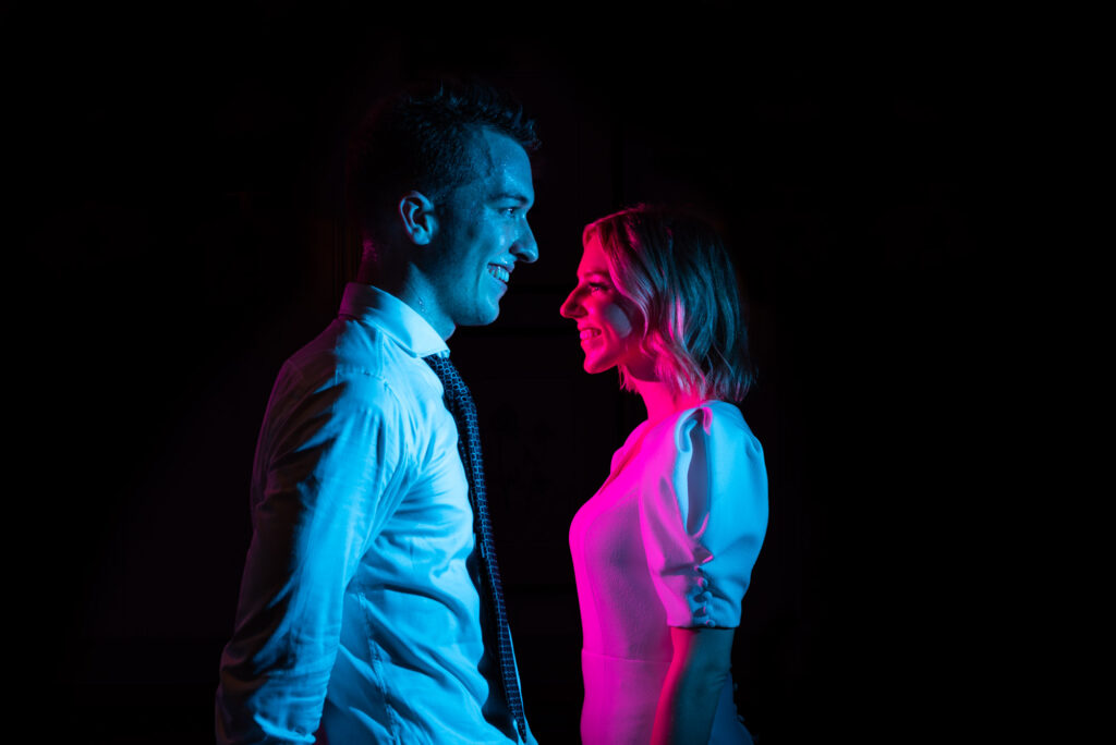 Bride and groom are lit with a blue and pink light